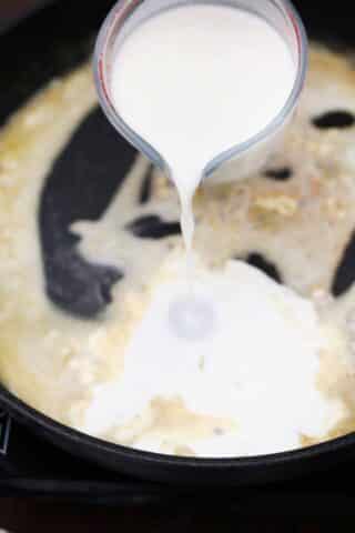 adding cream to melted butter and garlic mixture in a skillet