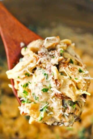 a serving wooden spoon with instant pot tuscan chicken pasta