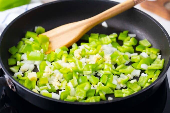 Cooking onion and bell pepper in a skillet.